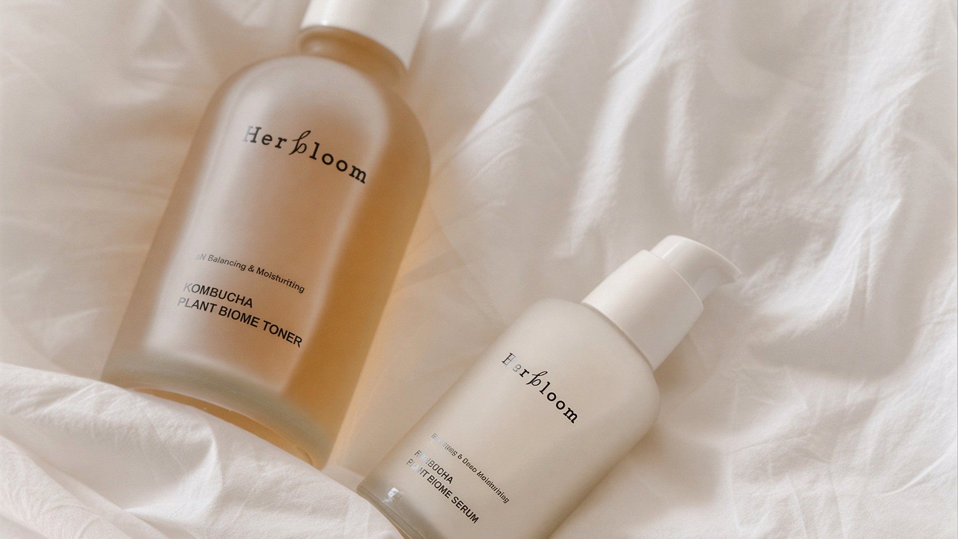 Three skincare products from derbloom on a soft white fabric background